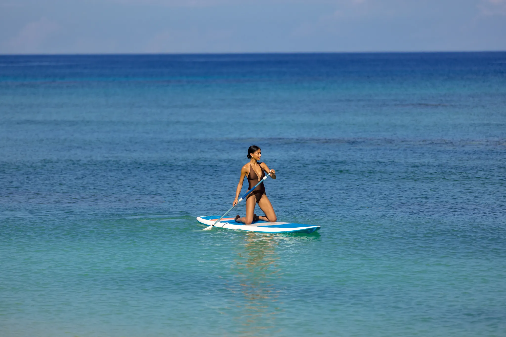Guest paddleboarding on crystal-clear Caribbean waters at Breathless Montego Bay.