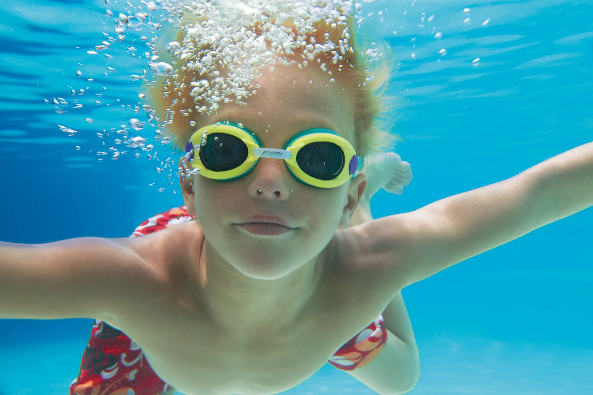 Child swimming underwater with goggles in the resort pool at Dreams Vallarta Bay Resort & Spa.