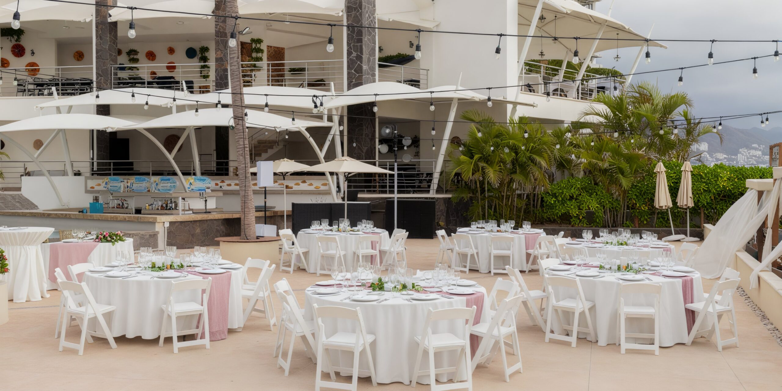 Pool deck wedding reception setup with round tables at Dreams Vallarta Bay Resort & Spa