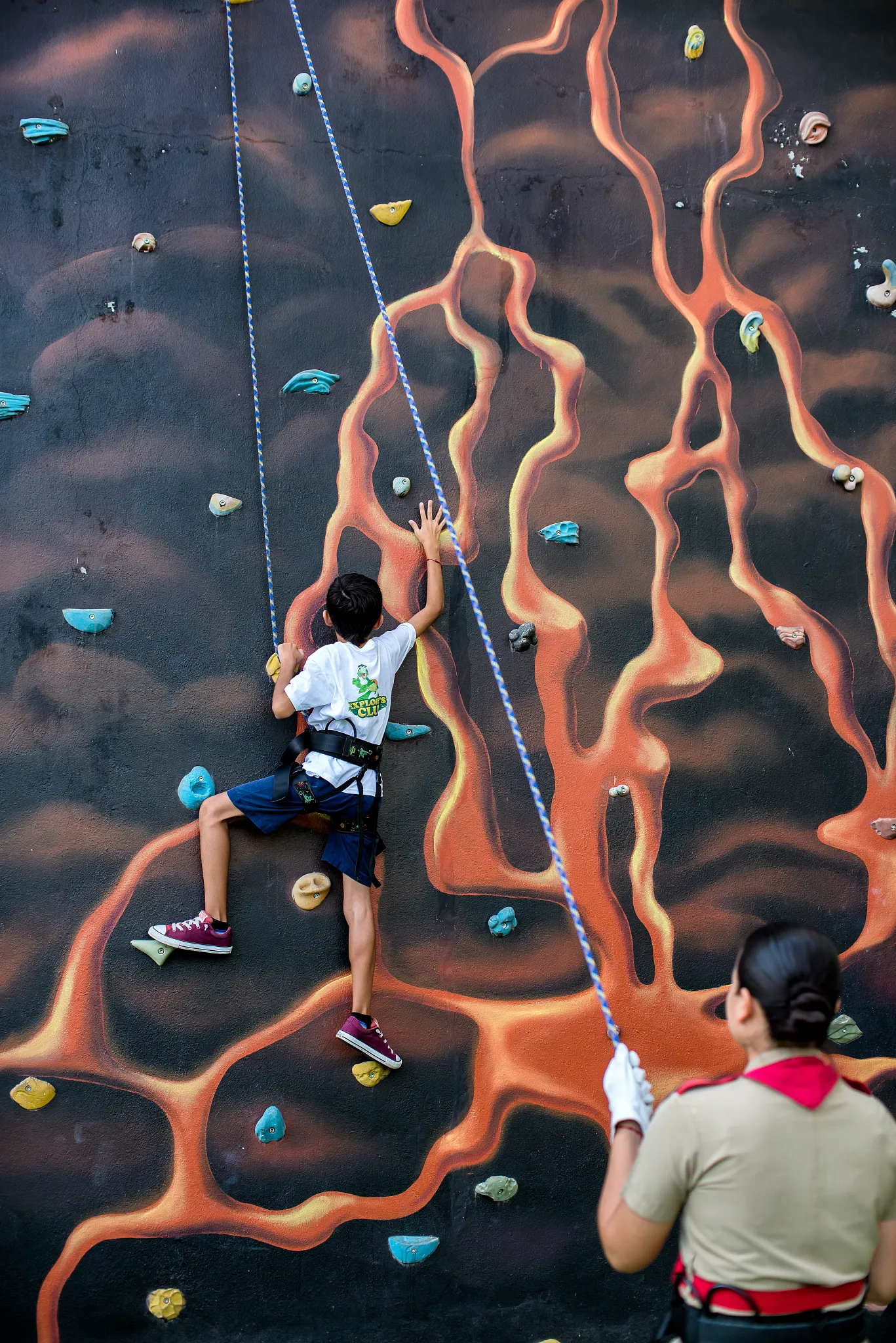Child climbing an adventure wall at Dreams Vallarta Bay Resort & Spa with staff supervision.