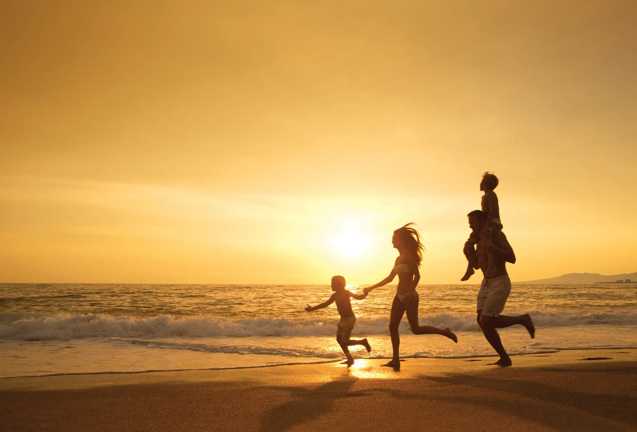 Family walking along the beach at sunset near Dreams Vallarta Bay Resort & Spa in Puerto Vallarta.