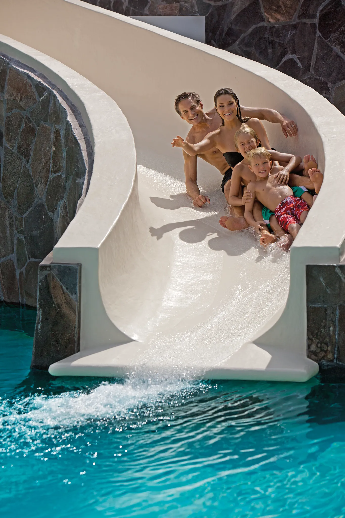 : Family sliding together into a pool at the Dreams Vallarta Bay Resort & Spa water slide.