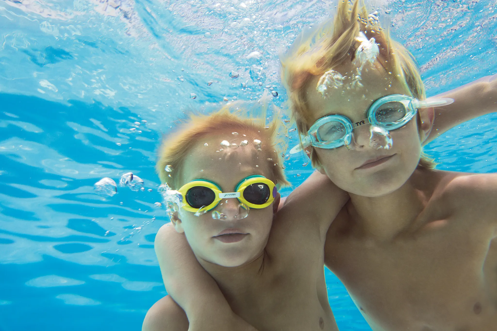 Two kids swimming underwater with goggles in the pool at Dreams Vallarta Bay Resort & Spa.