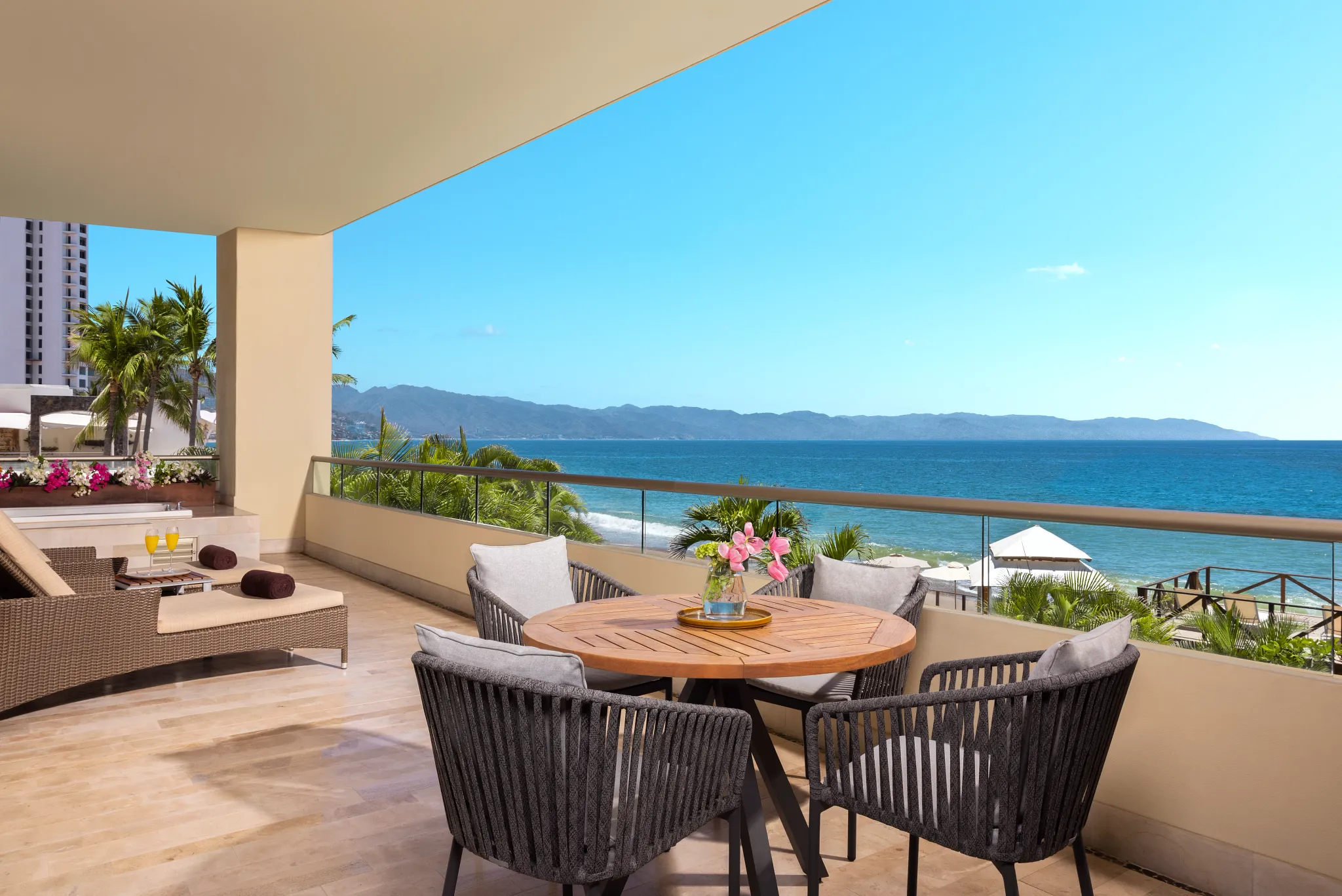 Oceanview terrace with dining table and seating at Dreams Vallarta Bay Resort & Spa overlooking Banderas Bay.